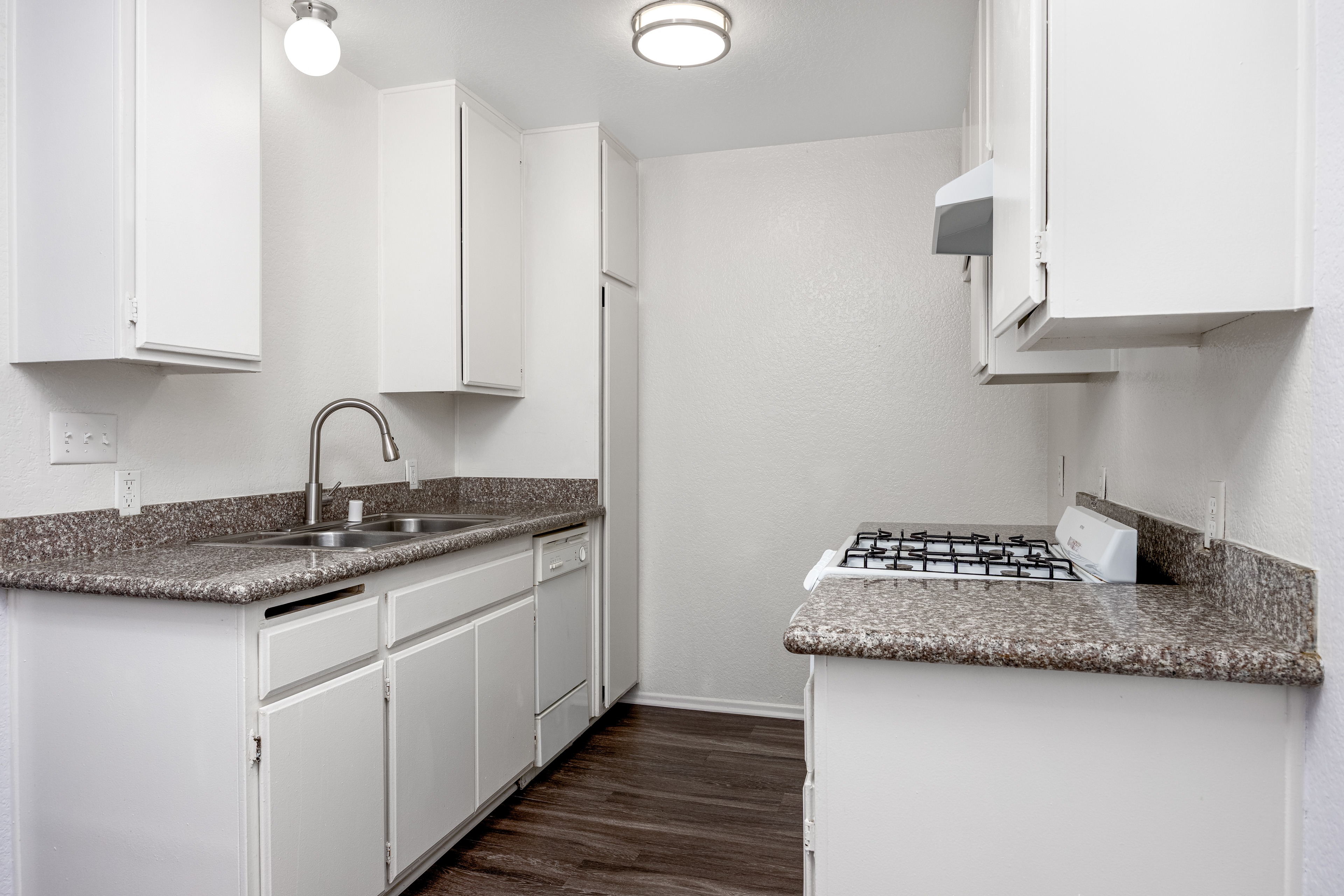 A kitchen with white cabinets and a granite countertop.